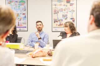 An image of two people sat at a table in a meeting