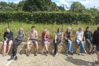 A photo of the Planit team laughing while sitting aligned on a stone wall