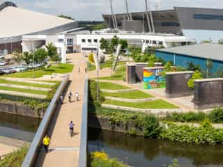 A birds eye view image of the Velopark, people cycle across the bridge towards it.