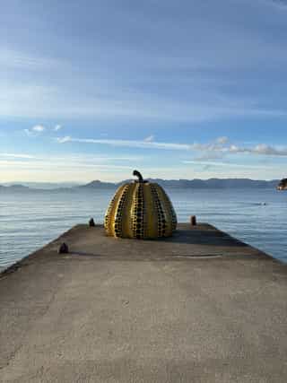 Repaired pottery using gold to create a sculpture of a pumpkin, on the edge of a bay on the ocean
