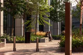 Residents using the seating wall outside the Angel Gardens apartment buildings which are surrounded by plating and include wayfinding signage in the NOMA brand.