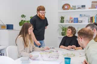 An image of four people gathered around a table laughing and discussing the design plans on the table