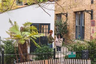 A woman and man outside a building, reading and discussing a book together