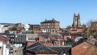 An image overlooking the tops of building in Stockport, with the church in the distance