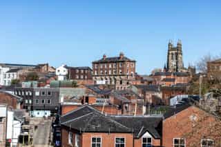 An image overlooking the tops of building in Stockport, with the church in the distance
