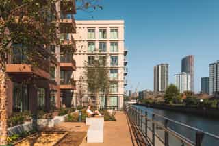 An image of a man lying on the seating looking out at a canal at Sugar House Island, he is surrounded by planting on a sunny day