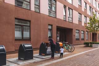 An image of a woman and her young daughter, the woman is using the large bins outside in Sugar House Island