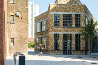 An wide angle image of a building as a man walks past, down a street
