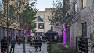 An image of the courtyard in Sugar House Island in use for an event, purple lighting against the walls and people networking