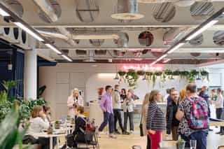 People at a networking event, some stood talking and some sat talking over a hot drink