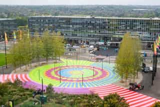 Aerial shot looking across at a bright mural painted on the ground infront of Milton Keynes Station
