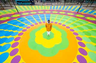 Image of Yinka Allori stood in the middle of a bright mural on the ground